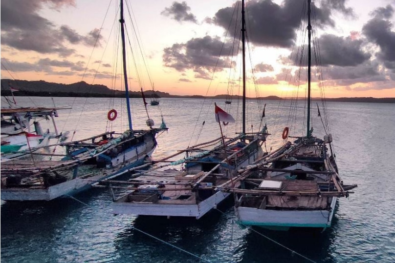 Wooden boats moored in a port at sunset.