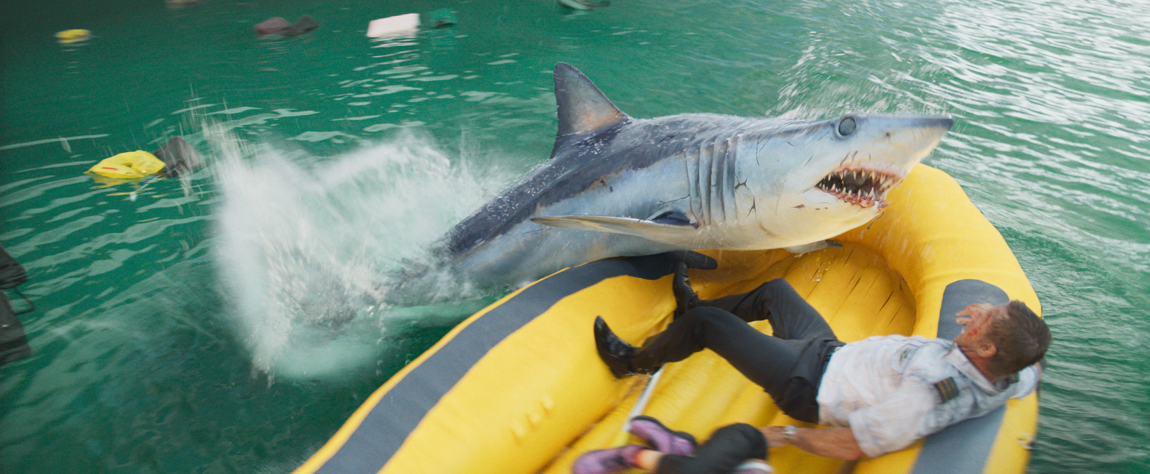 In an overhead shot from the 2026 shark movie Deep Water, a shark throws itself onto a yellow life raft holding an airline pilot played by Aaron Eckhart.