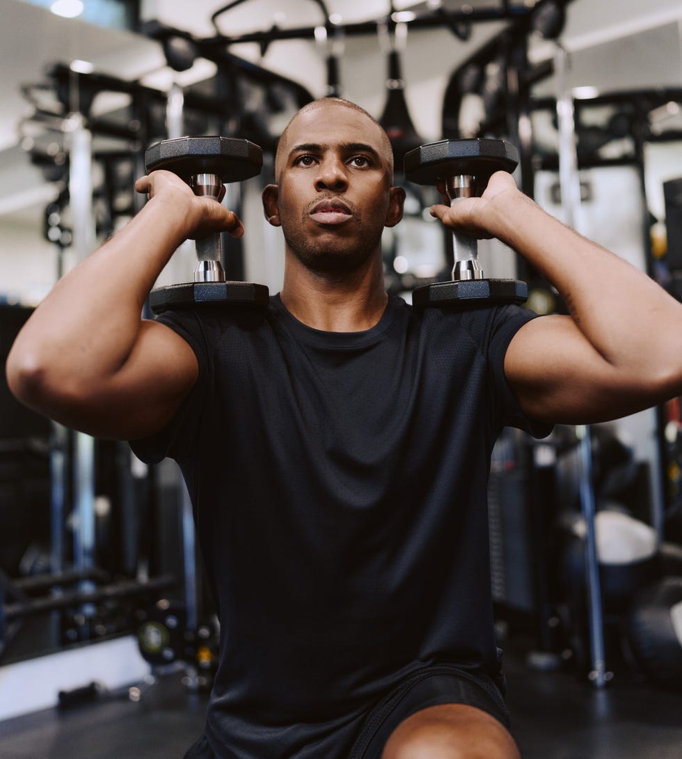 Person performing a weightlifting exercise in a gym.
