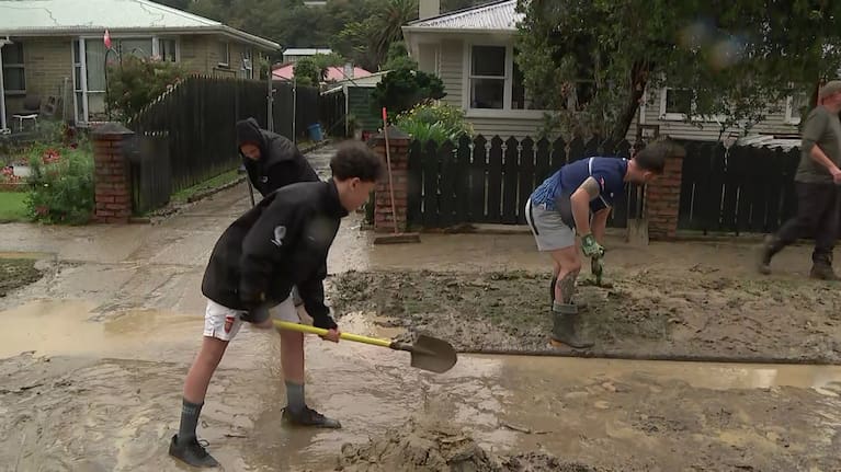 Eugene Grant (in blue) helps to clean up silt on his Stokes Valley street.