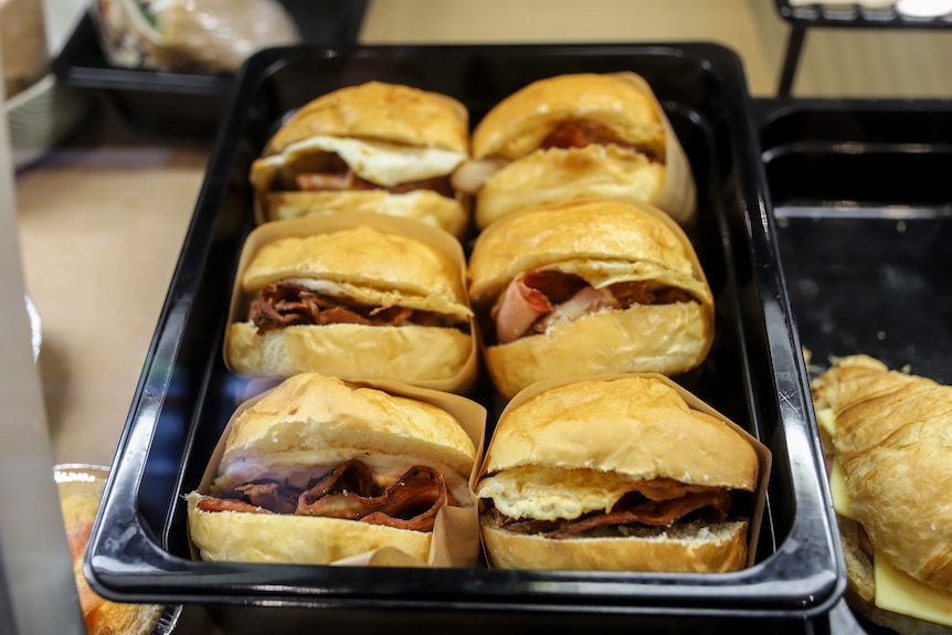 Two rows of bacon and egg rolls in cafe display window 