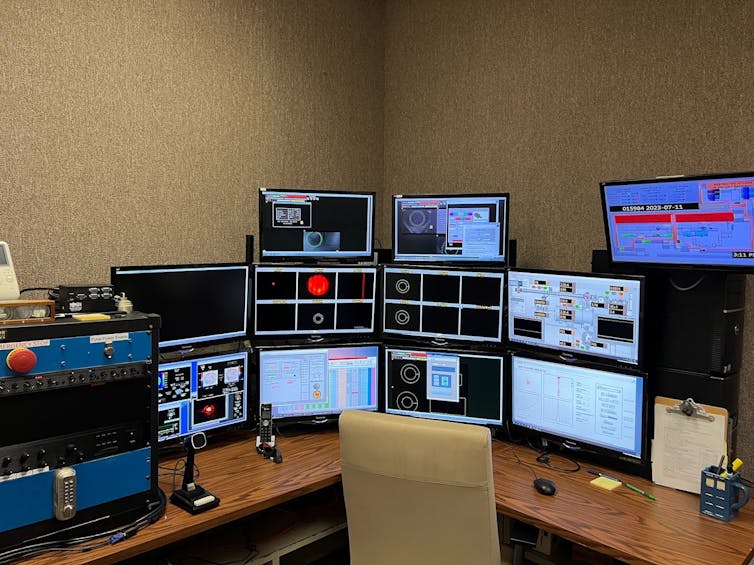 A desk with 11 monitors displaying graphs.