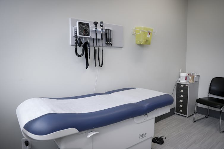 A medical examination room with an examination table and medical tools hanging about it
