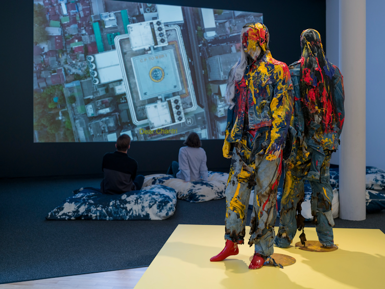 Two mannequins in front of a screen.