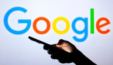Google's logo is shown behind a silhouette hand holding a smartphone.