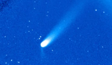 A comet is pictured in a coronagraph with a large sweeping tail extendin to the upper right of the screen.