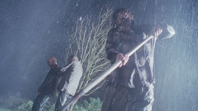 A man digging during a storm with two other men behind him