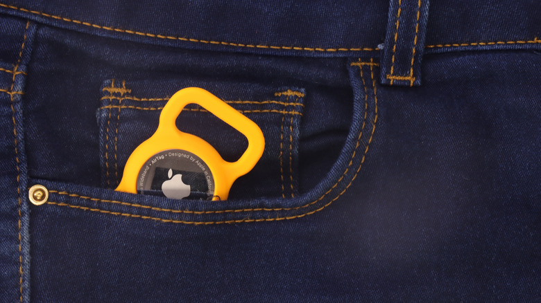 An Apple AirTag peeking out from a jeans pocket.