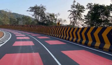 Red highway section in India with bright thermoplastic surface designed to slow drivers in a wildlife corridor with fencing and underpasses.