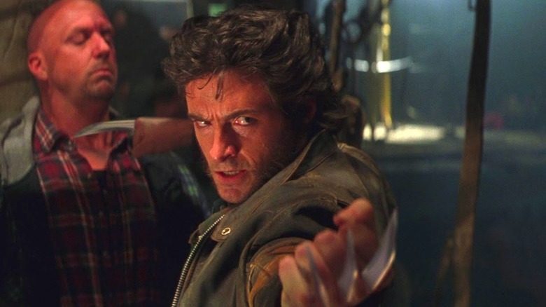 Hugh Jackman as Wolverine with his claws out threatening some guys in a bar in X-Men