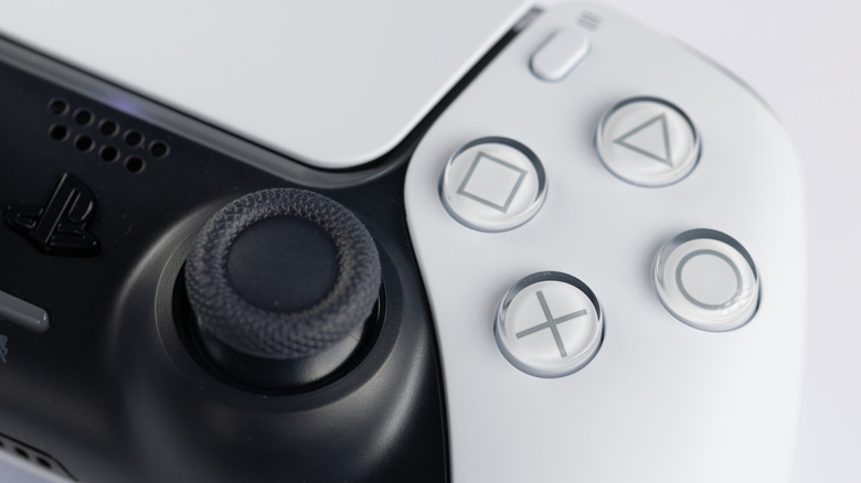 Close-up of DualSense controller showing analog stick and PlayStation face buttons.