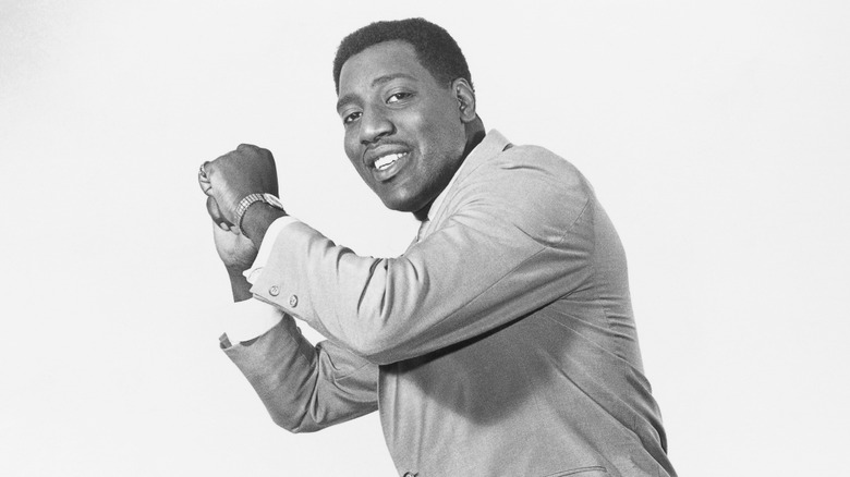 Otis Redding smiling in suit with fists raised