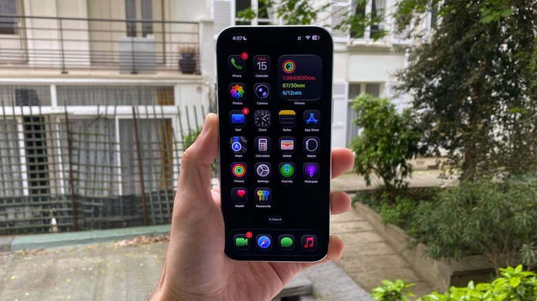 A hand holding an iPhone 17 Pro Max with Dark Mode and Tinted Icons on