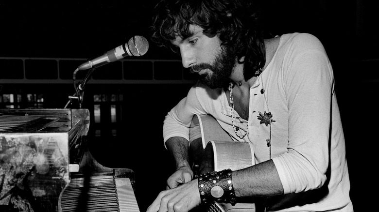 Cat Stevens playing piano and holding guitar