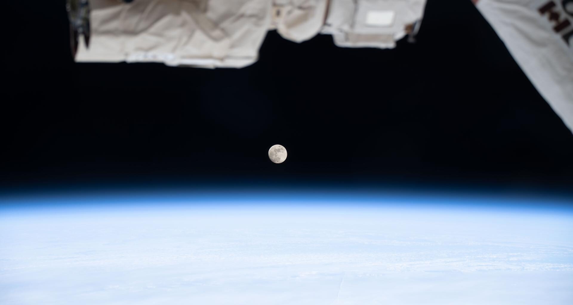 A waxing gibbous Moon is pictured above Earth's atmosphere from the International Space Station as it soared 268 miles above far eastern Canada. A portion of the Canadarm2 robotic arm's latching end effector is captured in the top foreground of the image.