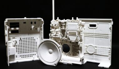a hyperrealistic, scale sculpture of a small radio made from white paper, deconstructed to show its inner parts