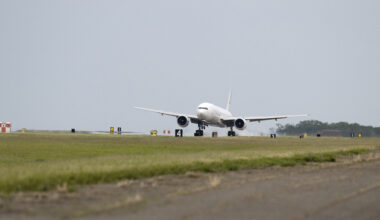 The white 777 aircraft can be seen touching down on a long runway with a row of grass along the pavement at NASA's Langley Research Center.