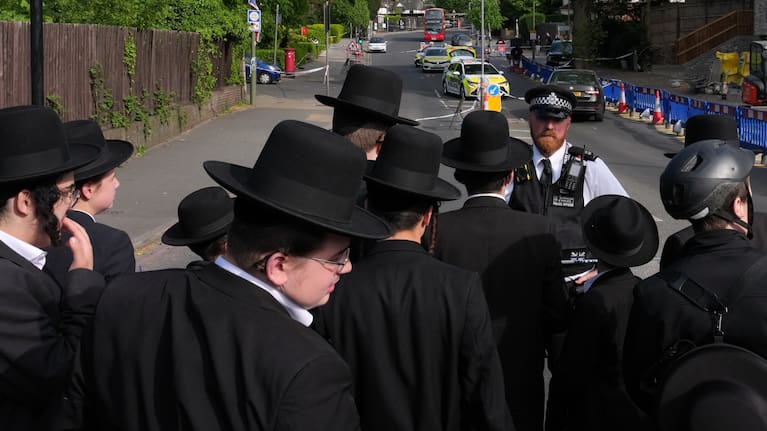 Members of the community watch as forensic officers search the area after two people were stabbed in the Golders Green neighbourhood, that has a large Jewish community, in London.