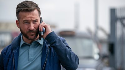 A man on a mobile phone looks at something off screen