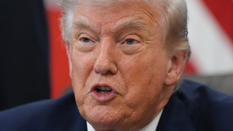 President Donald Trump answers questions from reporters after signing an executive order in the Oval Office.