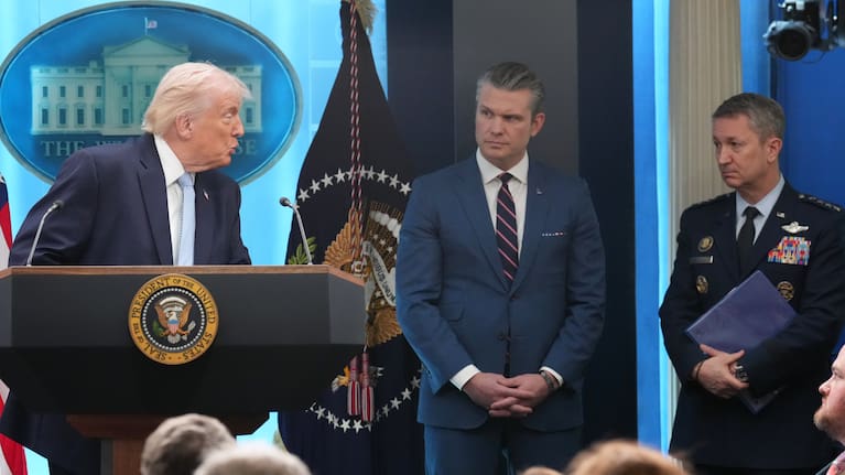 President Donald Trump looks to Defense Secretary Pete Hegseth and Chairman of the Joint Chiefs of Staff Gen. Dan Caine as he speaks with reporters during a news conference
