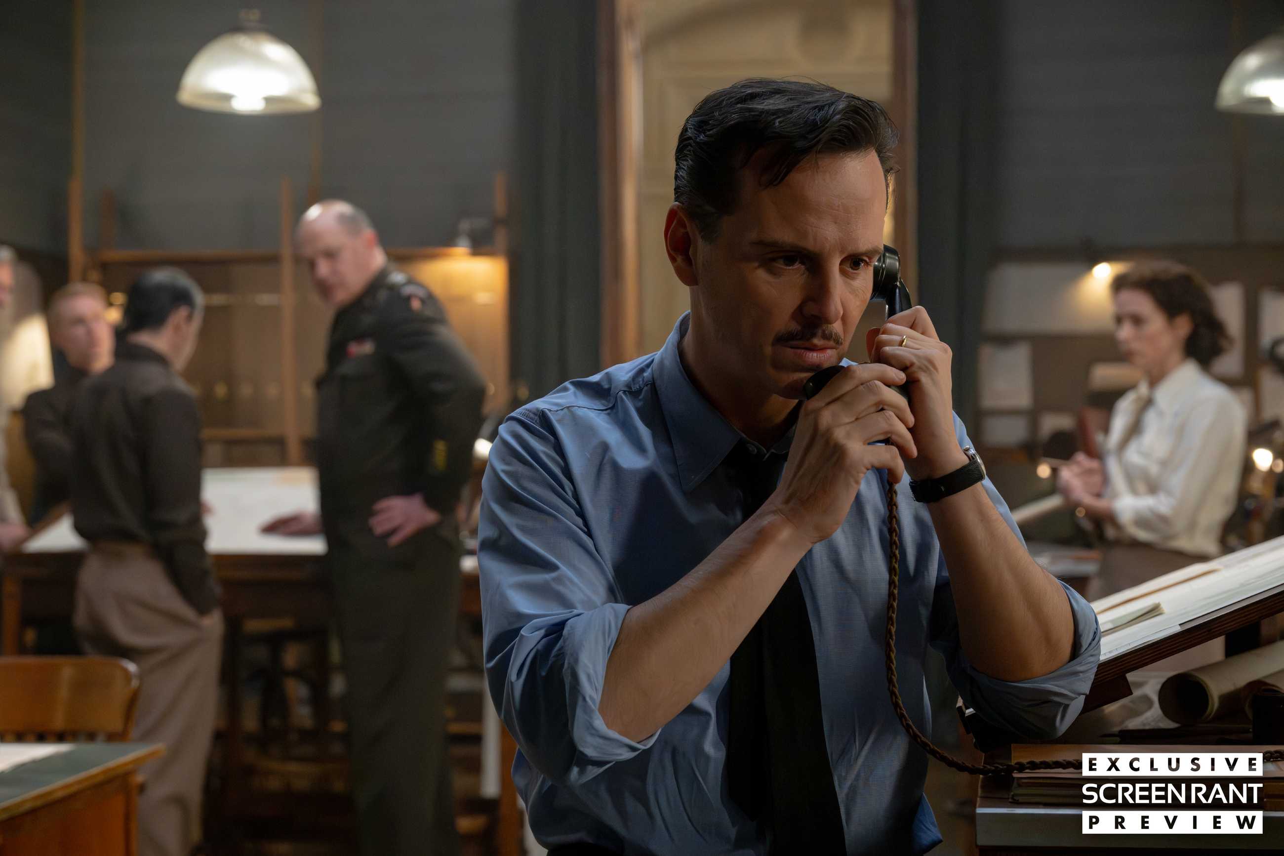 Andrew Scott clutching a phone with concern in the foreground with Brendan Fraser and Kerry Condon out of focus over his shoulder