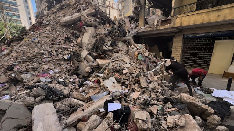 Residents stand next to the rubble of a destroyed building that was hit a week ago in an Israeli airstrike in central Beirut, Lebanon.