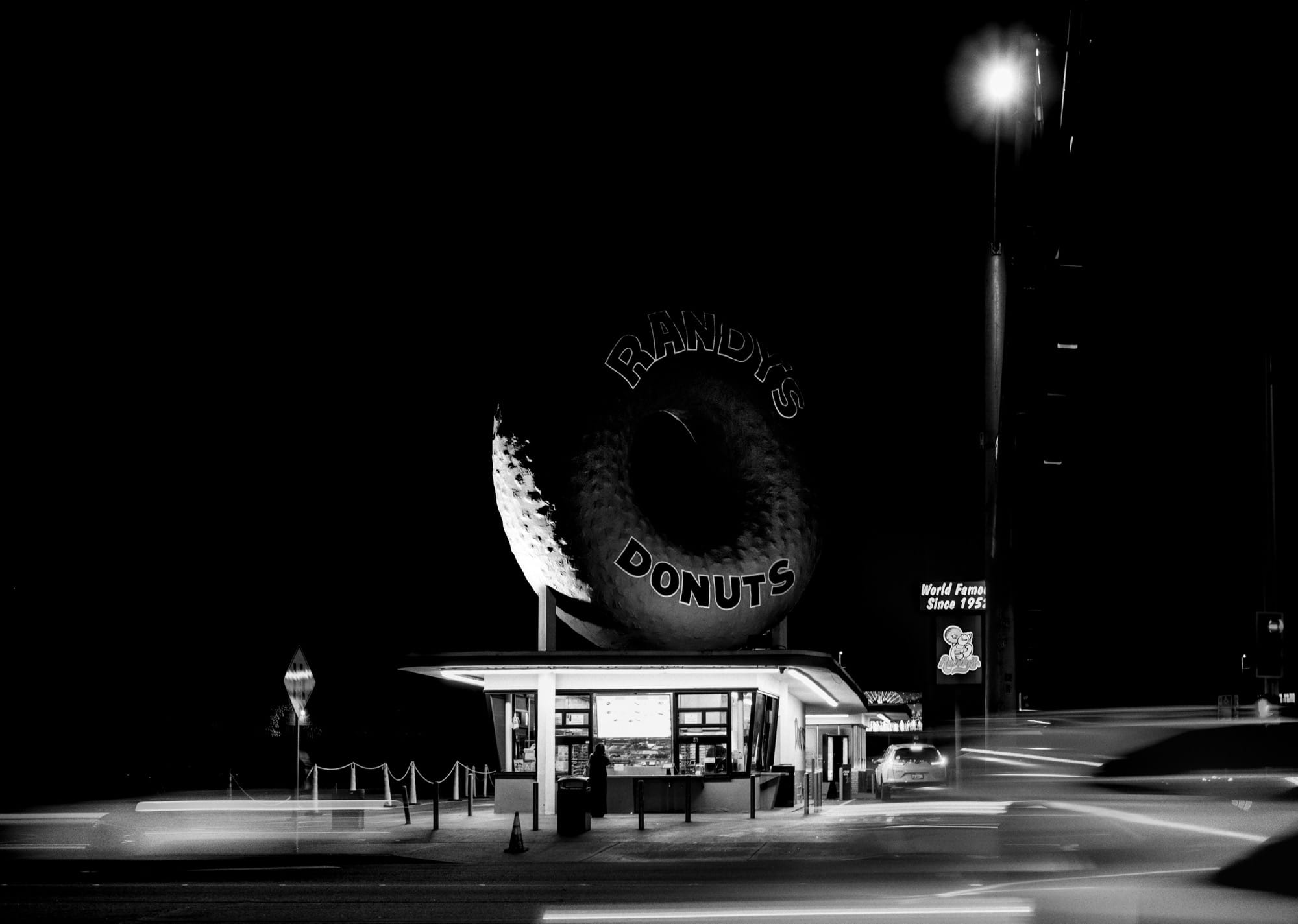a black-and-white photograph by Daniel Sackheim in a noir style of Randy's Donuts in Los Angeles