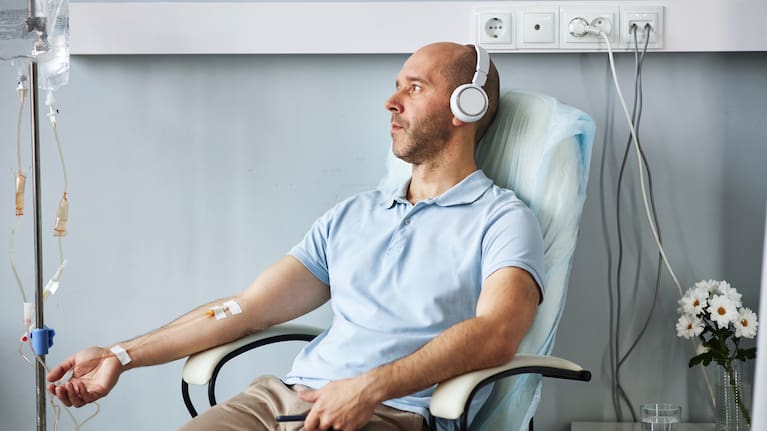 Side view portrait of adult man wearing headphones and listening to music during IV drip treatment in clinic (file image).
