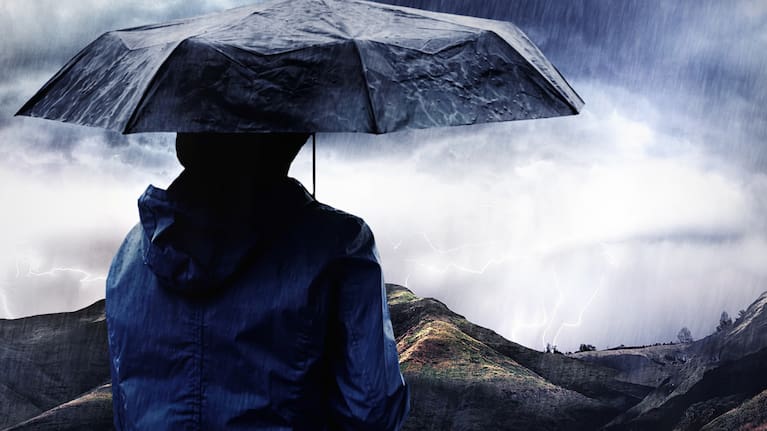 A person with an umbrella standing in a storm.