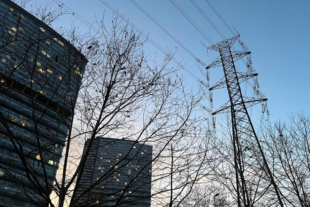 Electric transmission tower rises over high-rise buildings at dusk in Istanbul, Türkiye. (Adobe Stock Photo)
