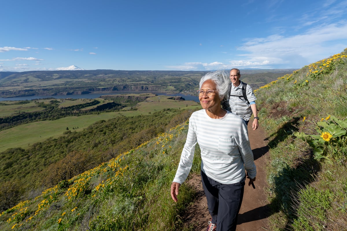 Two people outside walking on a trail.