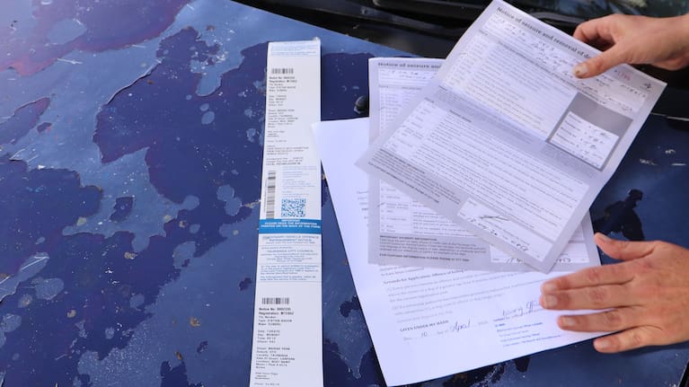 Vehicle-dweller Samantha Bradley shows the notices of fines she received on Monday morning.