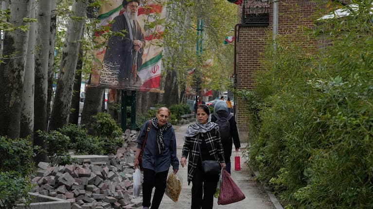 Women walk past a banner depicting the late Iranian Supreme Leader Ayatollah Ali Khamenei, who was killed in the U.S. and Israel strikes on Feb. 28, in northern Tehran, Iran.