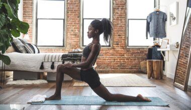 woman on an exercise mat performing a hip flexor stretch. she's sideways to the camera in a living room setting on wooden floors and exposed brick walls and windows behind her