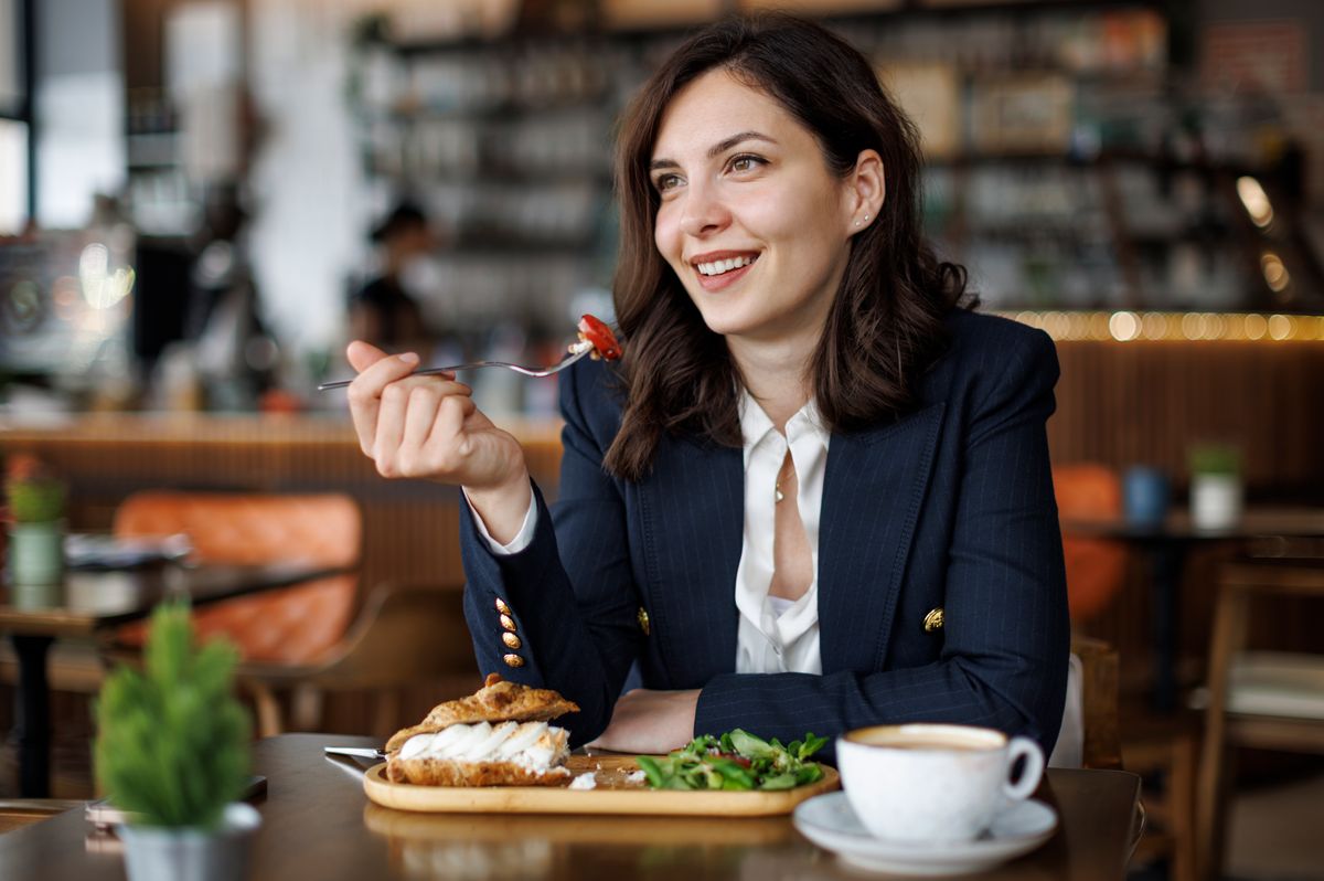 A smiling businesswoman enjoys breakfast while taking a short break in a modern café