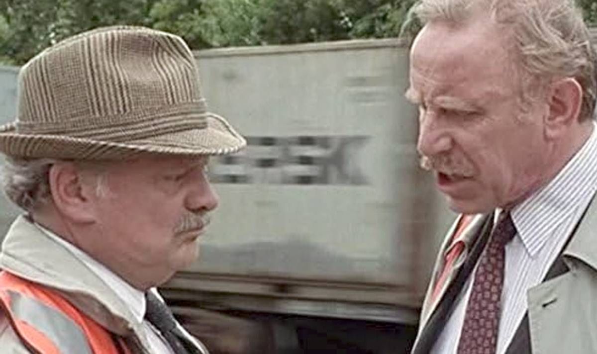 Two men talk in front of a train