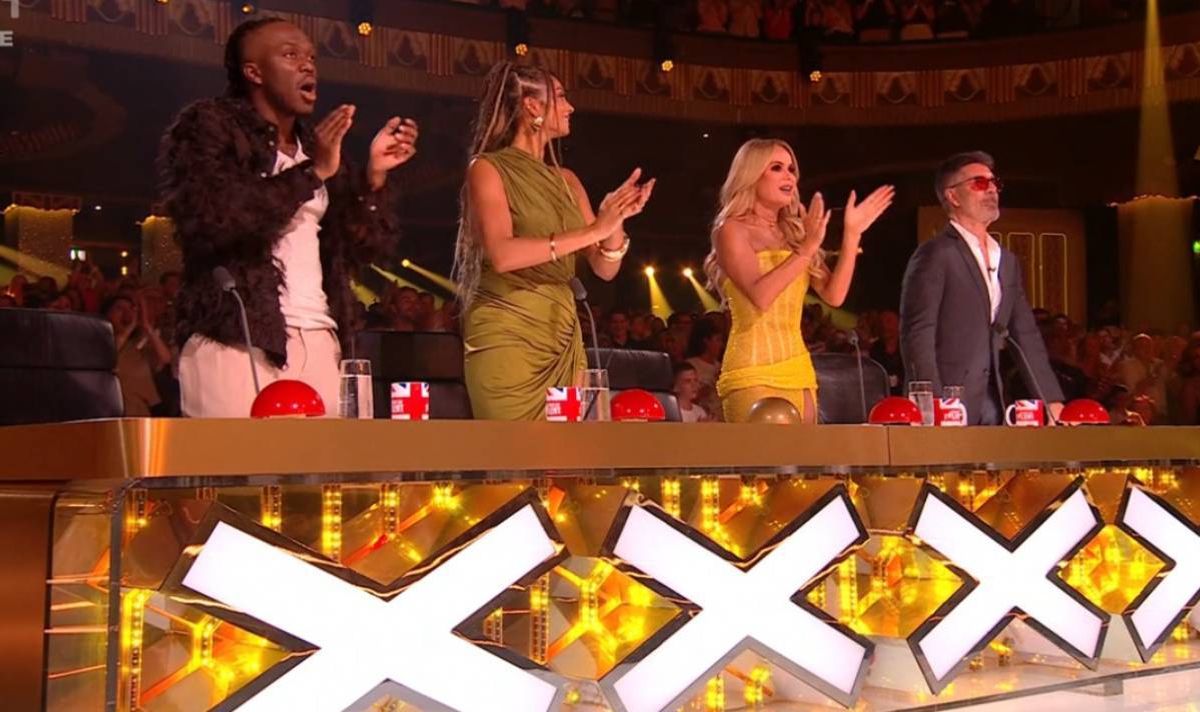 Two men and two women standing up behind a desk