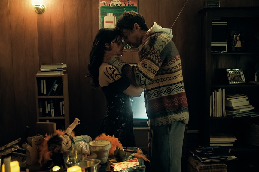 Two people embrace in a dirty apartment.