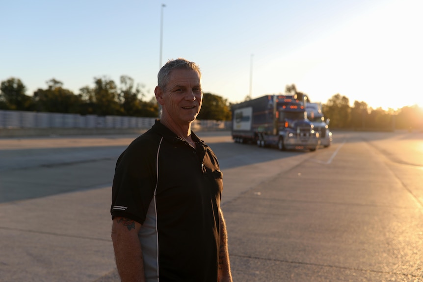 Sean Mulvaney stands in a changeover yard and smiles as the afternoon sun sets behind him