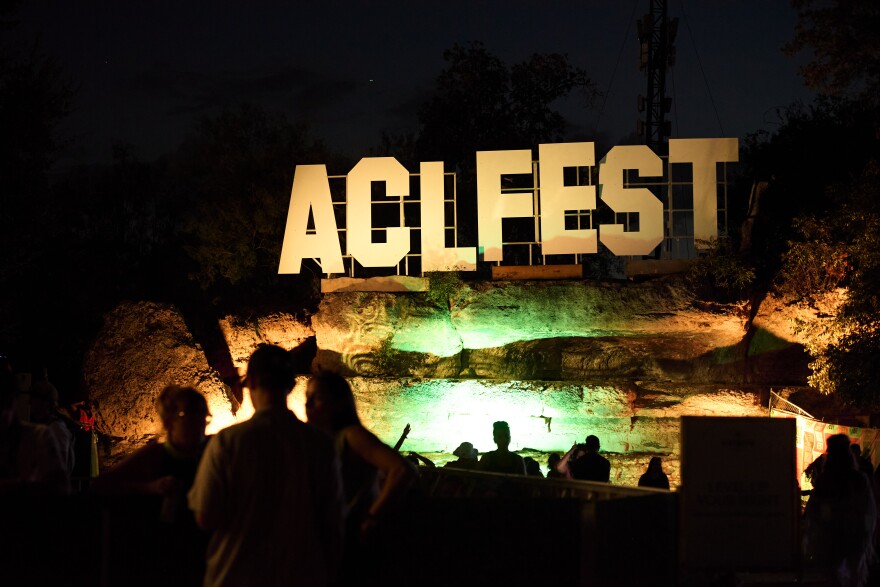 A sign reading ACL is brightly lit with people in front of it.