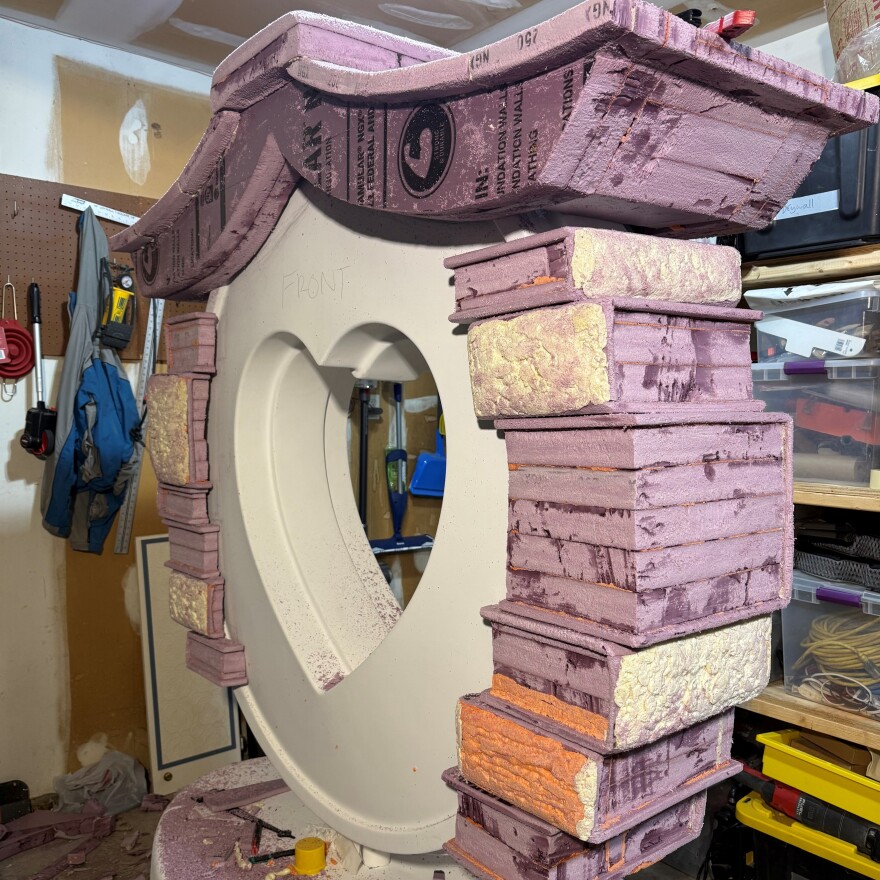 A large heart-shaped sculpture with pink foam being shaped around the edges to look like books.