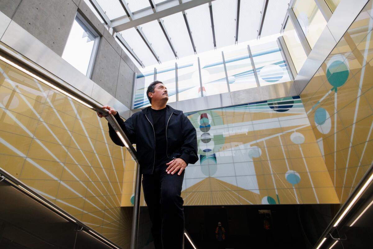 Artist Eamon Ore-Giron stands in front of his artwork at the Wilshire/La Brea Metro Station