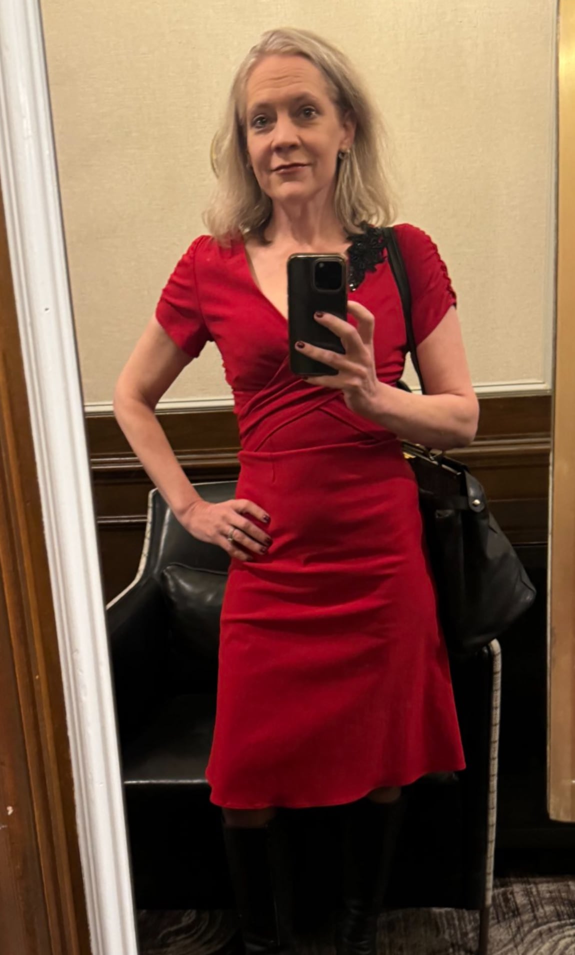 A slender woman in a red dress taking a selfie in a mirror.