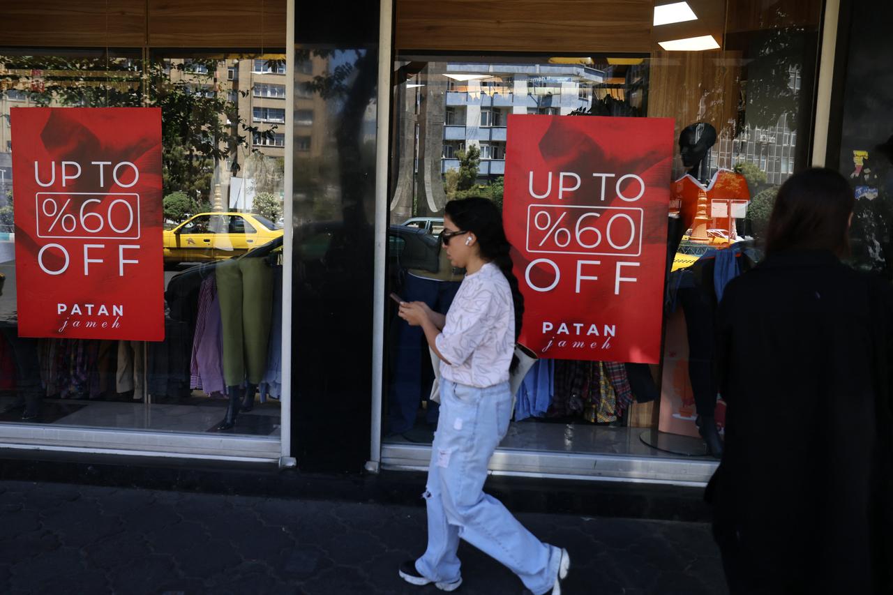 An Iranian woman walks past a boutique with posters advertising sales, in the capital Tehran, May 9, 2026. (AFP Photo)