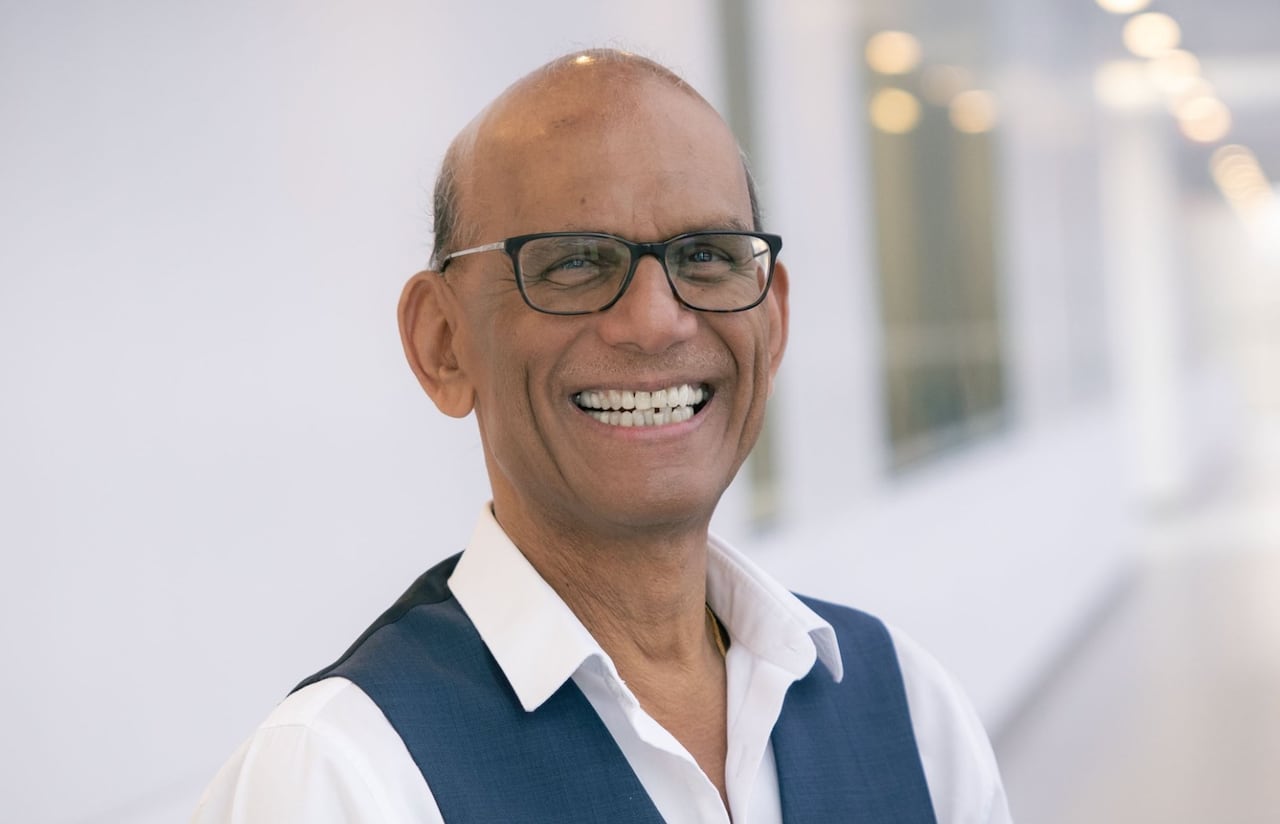 A man standing in a hallway smiles.