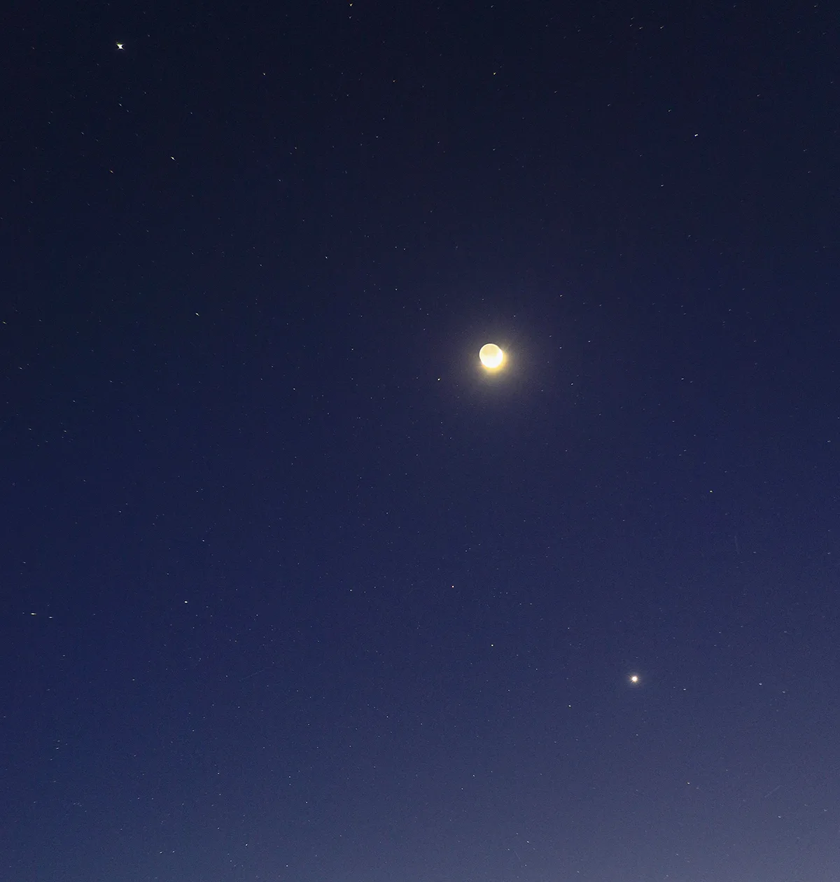 A beautiful view of the crescent Moon with Venus (bottom right) and Jupiter (top left), captured by Giovanni Passalacqua from Marina di Modica, Sicily, Italy, 19 May 2026. Equipment: Canon EOS R DSLR camera, Sigma 35mm lens, Manfrotto tripod. Exposure: ISO 2000, f/2.2, 2.8s Software: Photoshop