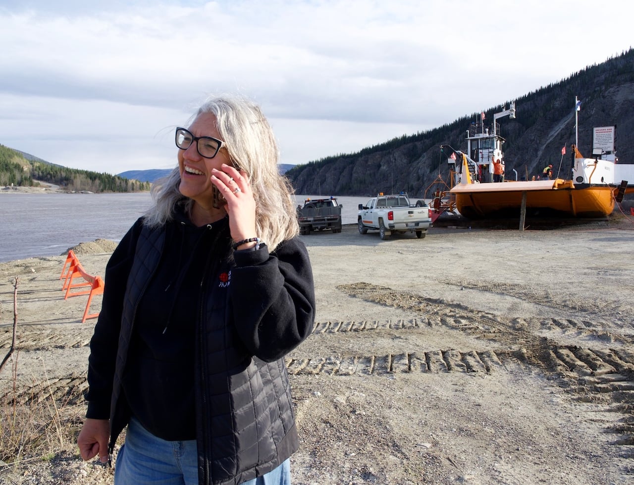 CBC's Elyn Jones stands near the ferry in Dawson City