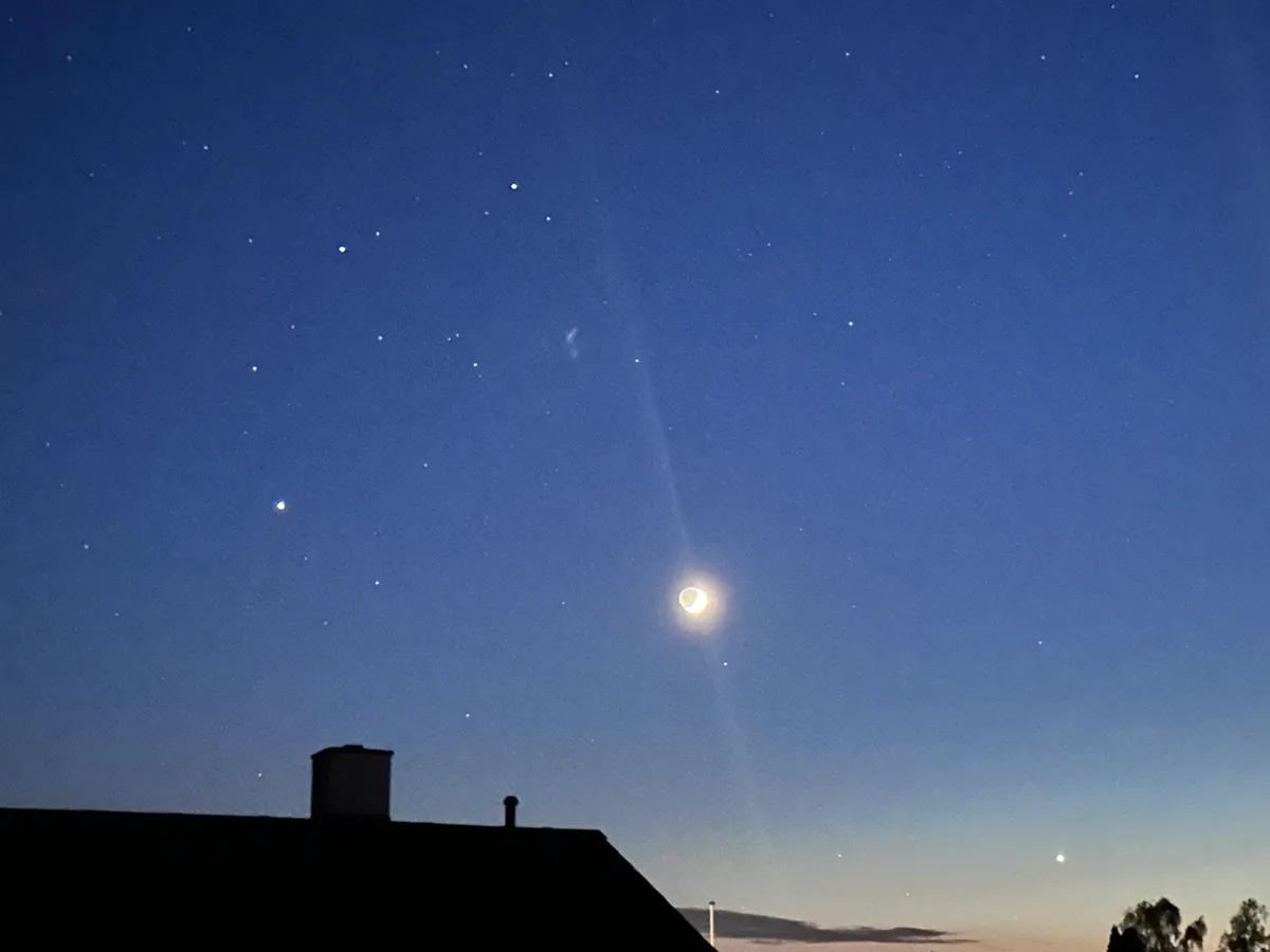 Amanda Millard sent us this view of Venus, the crescent Moon and Jupiter from Fensmark, Zealand, Denmark, 19 May 2026. Venus is on the bottom right of the image. Jupiter is on the left, above the chimney top. The two brightest stars above Jupiter, forming an isosceles triangle with the Moon, are Castor and Pollox, the twin stars of Gemini.