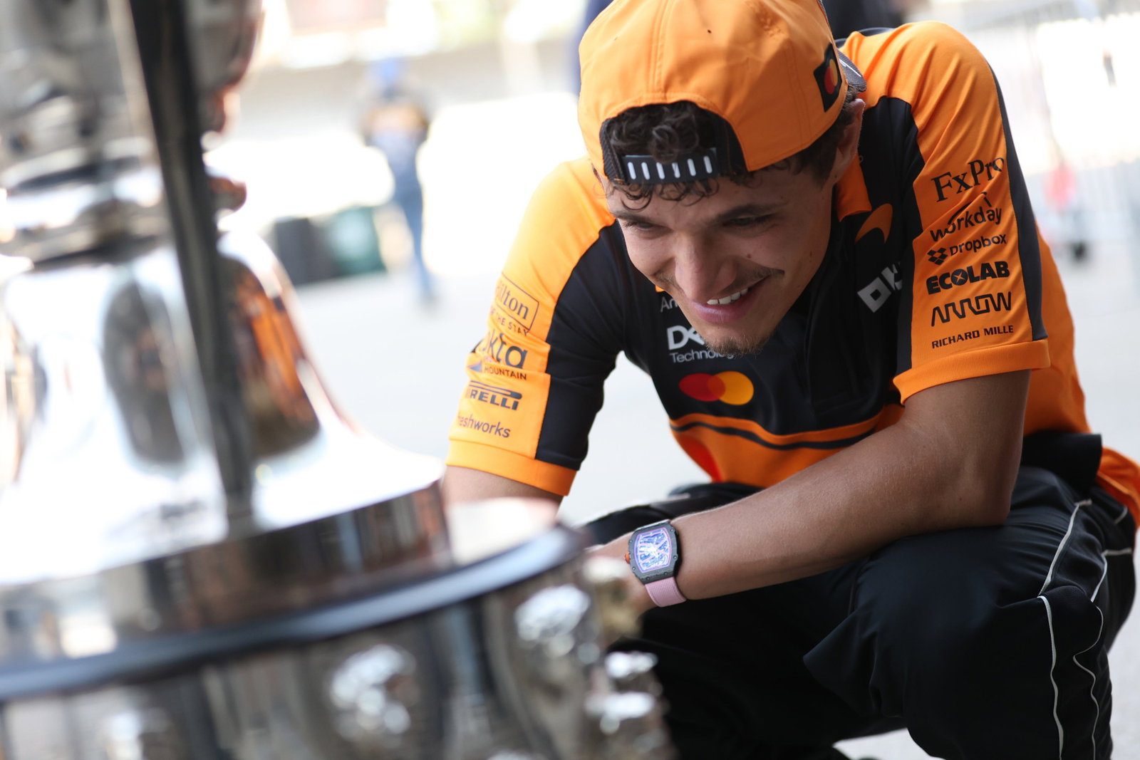 McLaren driver Lando Norris inspects the Borg Warner Trophy.